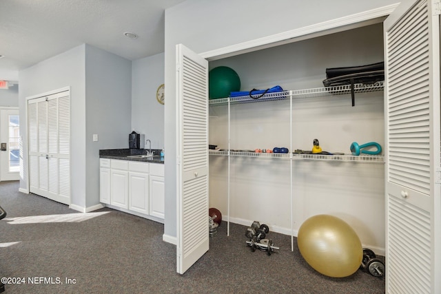 workout room featuring dark colored carpet and sink