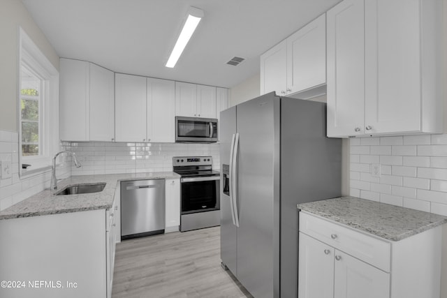 kitchen featuring backsplash, stainless steel appliances, sink, light hardwood / wood-style flooring, and white cabinetry