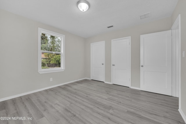 unfurnished bedroom with a textured ceiling and light hardwood / wood-style flooring