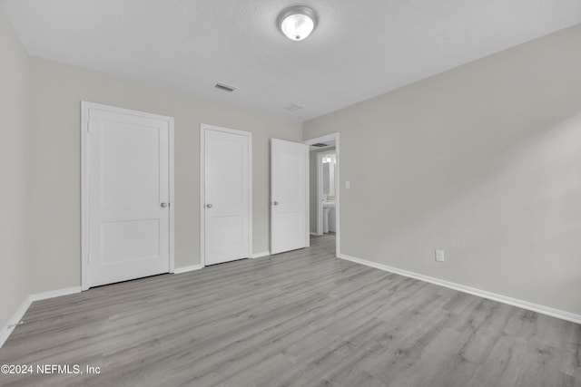 unfurnished bedroom with light hardwood / wood-style floors and a textured ceiling