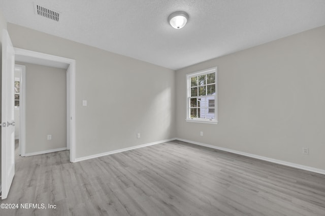 spare room featuring a textured ceiling and light hardwood / wood-style flooring