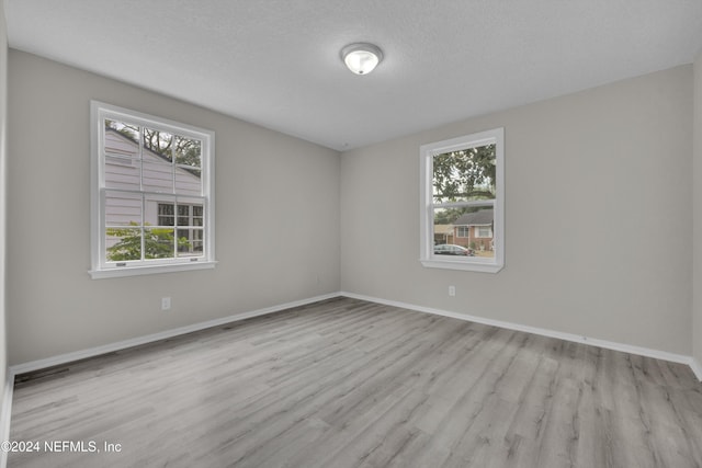 unfurnished room with a textured ceiling and light wood-type flooring