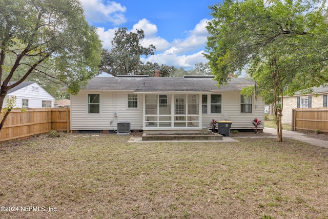 rear view of property featuring a sunroom, a yard, and cooling unit