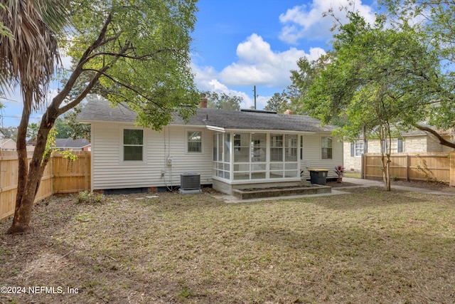 rear view of house featuring a sunroom, a yard, and central AC unit