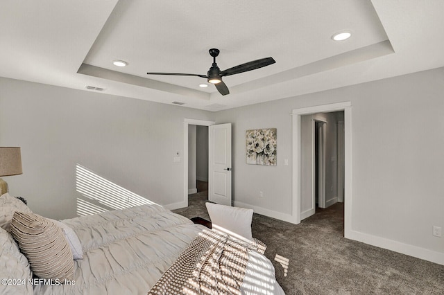 carpeted bedroom with a tray ceiling and ceiling fan