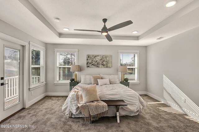 bedroom featuring ceiling fan, a raised ceiling, a textured ceiling, and access to outside