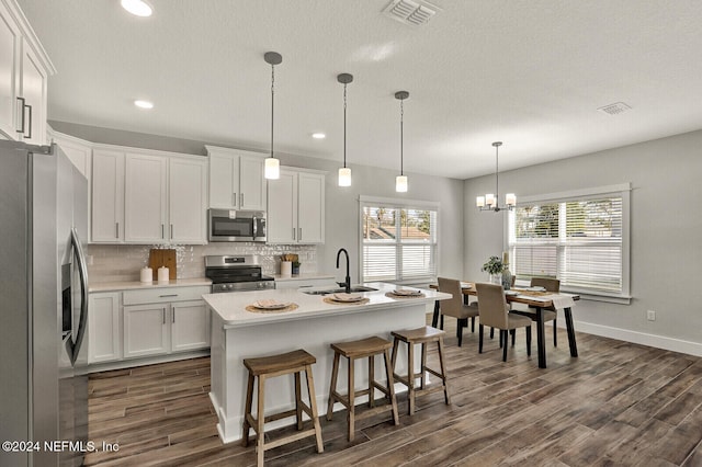 kitchen with white cabinets, appliances with stainless steel finishes, and a center island with sink