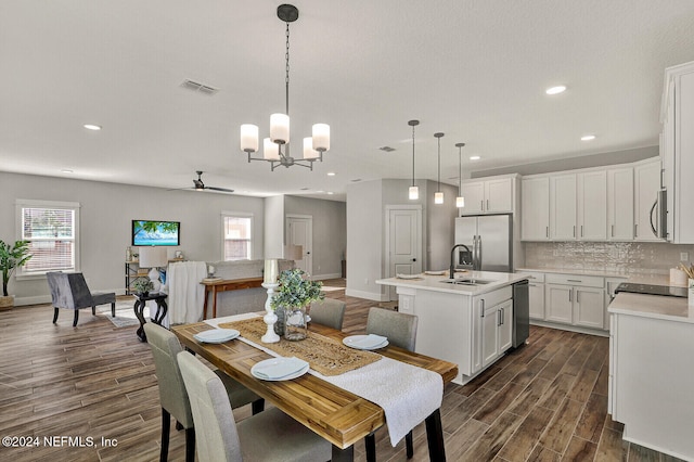 dining space featuring ceiling fan with notable chandelier and sink