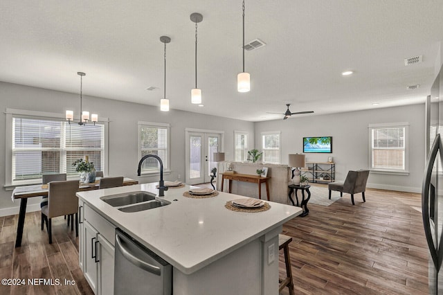 kitchen with sink, hanging light fixtures, stainless steel dishwasher, an island with sink, and white cabinets