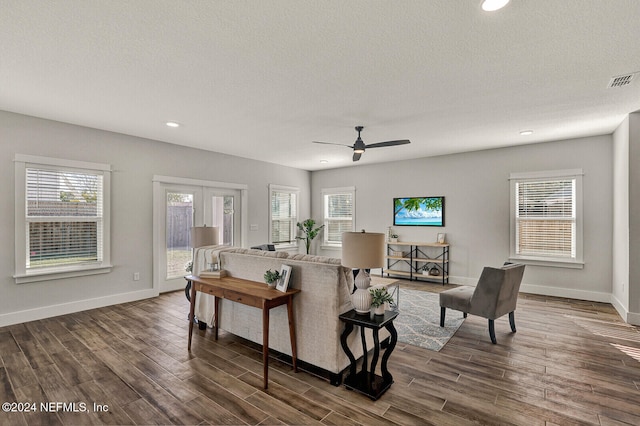 living room featuring a textured ceiling, ceiling fan, and dark wood-type flooring