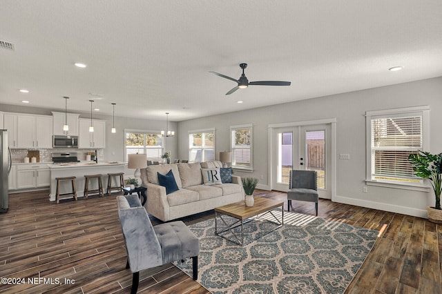 living room with french doors, dark wood-type flooring, ceiling fan with notable chandelier, and sink