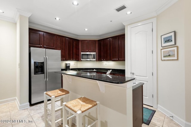 kitchen with light tile patterned floors, stainless steel appliances, crown molding, and a breakfast bar area