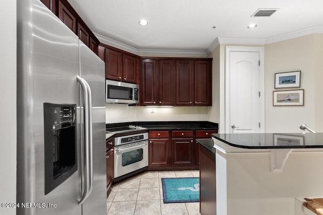 kitchen featuring dark stone countertops, light tile patterned flooring, crown molding, and stainless steel appliances