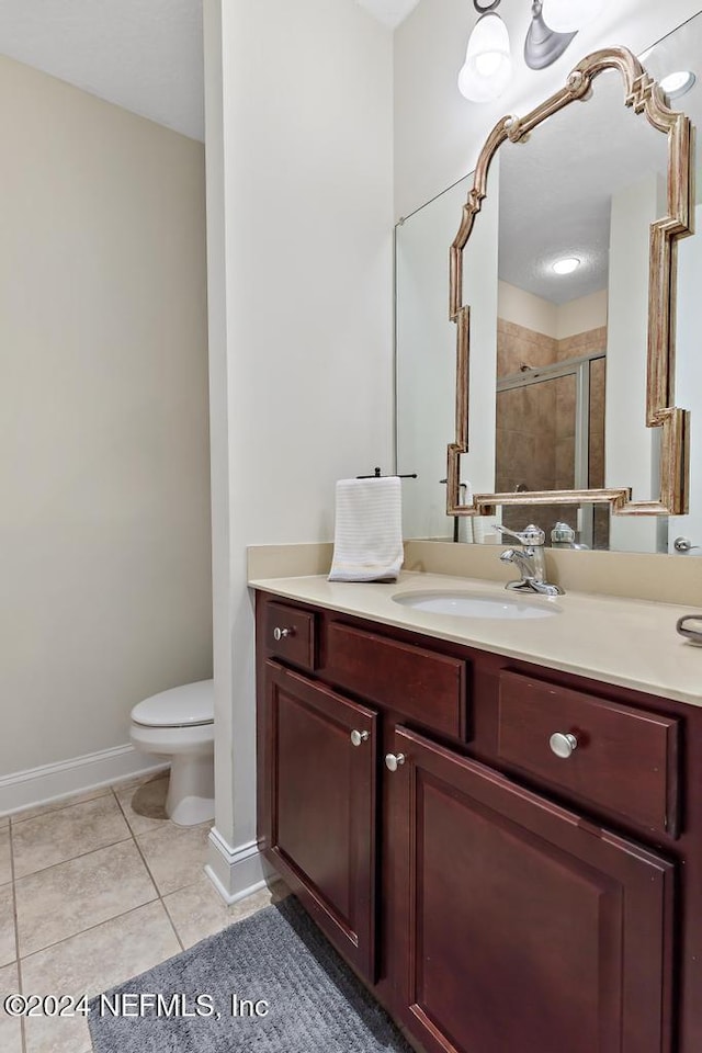 bathroom with tile patterned flooring, vanity, toilet, and walk in shower