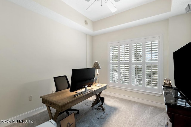 office area with a tray ceiling, ceiling fan, and carpet