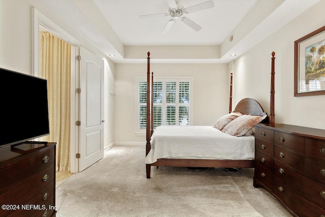 bedroom with a tray ceiling, ceiling fan, and light colored carpet