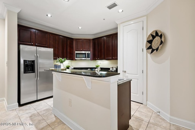 kitchen with dark stone countertops, appliances with stainless steel finishes, light tile patterned floors, a kitchen island, and a breakfast bar area