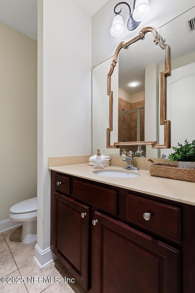 bathroom with tile patterned floors, toilet, a shower with door, and vanity