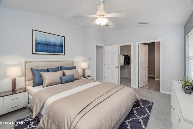 bedroom with ceiling fan, lofted ceiling, a walk in closet, light carpet, and a closet