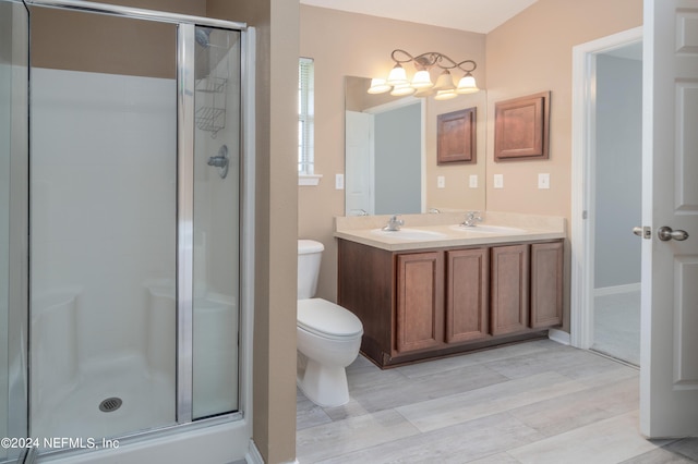 bathroom featuring a shower with door, vanity, and toilet