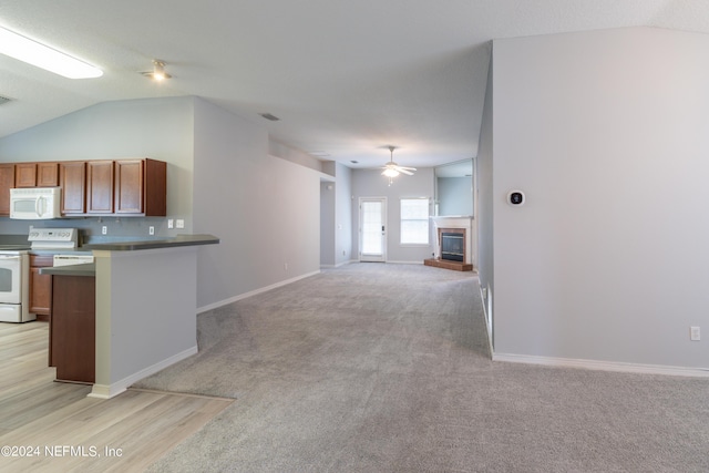 kitchen with kitchen peninsula, light carpet, white appliances, vaulted ceiling, and ceiling fan