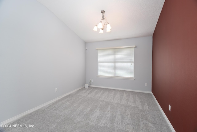 spare room with light carpet, lofted ceiling, and an inviting chandelier