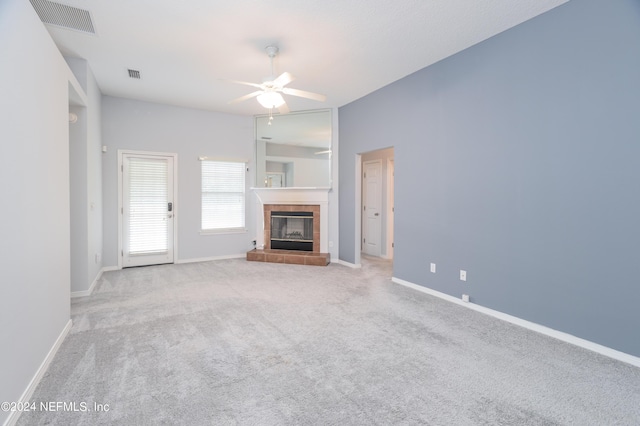 unfurnished living room featuring ceiling fan, light carpet, and a tiled fireplace