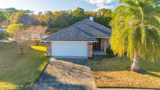 view of front of house featuring a water view, a garage, and a front lawn