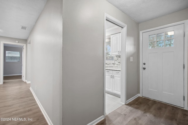 entryway with a textured ceiling and light wood-type flooring