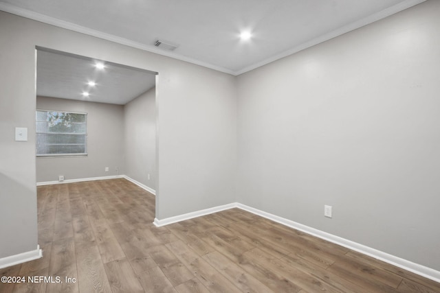 empty room featuring light hardwood / wood-style flooring and crown molding