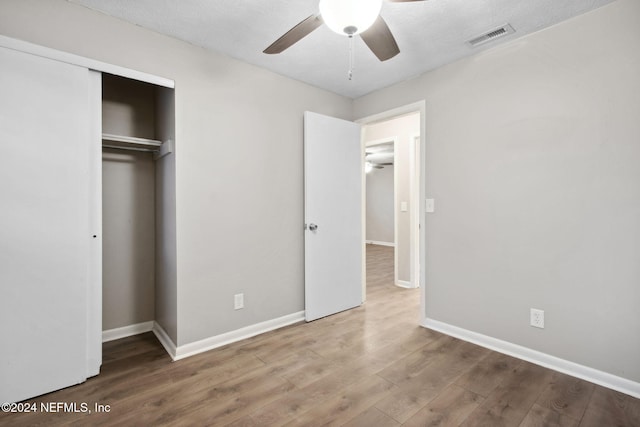 unfurnished bedroom featuring ceiling fan, wood-type flooring, a textured ceiling, and a closet