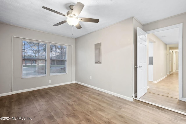 spare room featuring electric panel, ceiling fan, and wood-type flooring