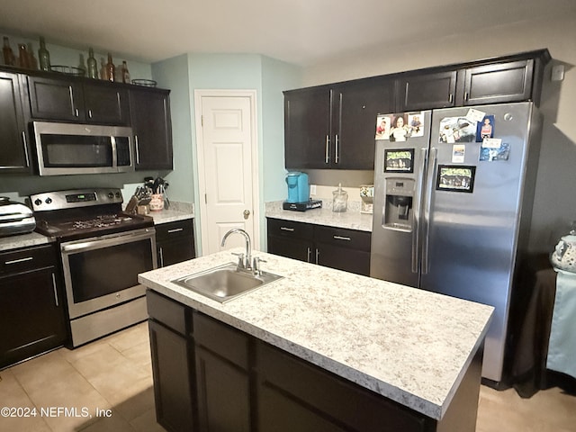 kitchen featuring a kitchen island with sink, sink, light tile patterned floors, and stainless steel appliances