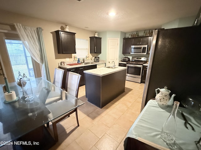 kitchen featuring sink, dark brown cabinetry, stainless steel appliances, and an island with sink