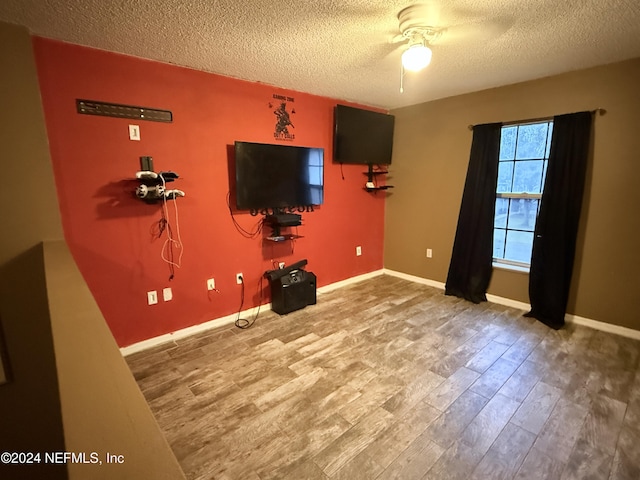 unfurnished living room with hardwood / wood-style flooring, ceiling fan, and a textured ceiling