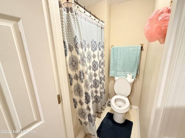 bathroom featuring tile patterned flooring, toilet, and walk in shower