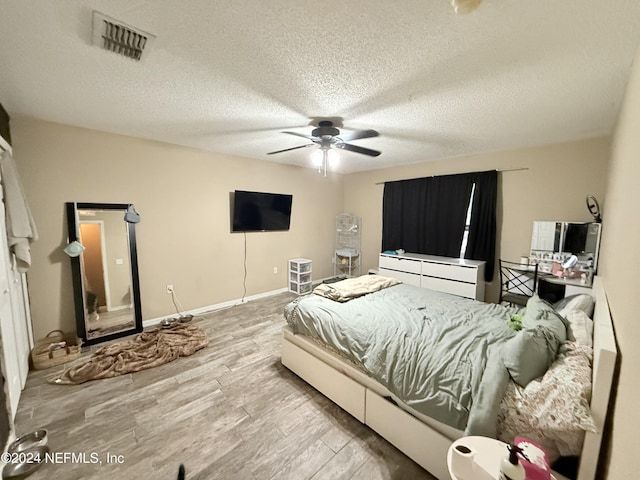 bedroom with ceiling fan, a textured ceiling, and light wood-type flooring