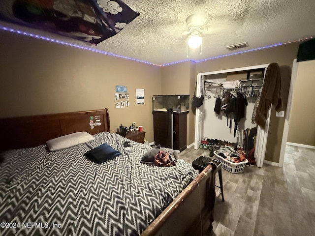 bedroom with ceiling fan, a closet, wood-type flooring, and a textured ceiling