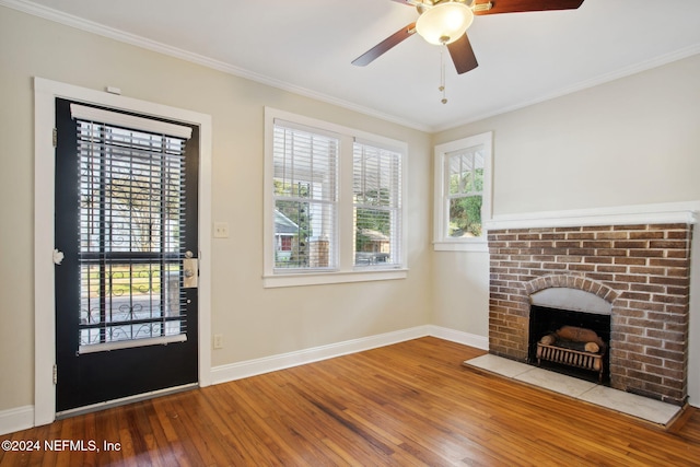 unfurnished living room featuring a brick fireplace, ceiling fan, wood-type flooring, and ornamental molding