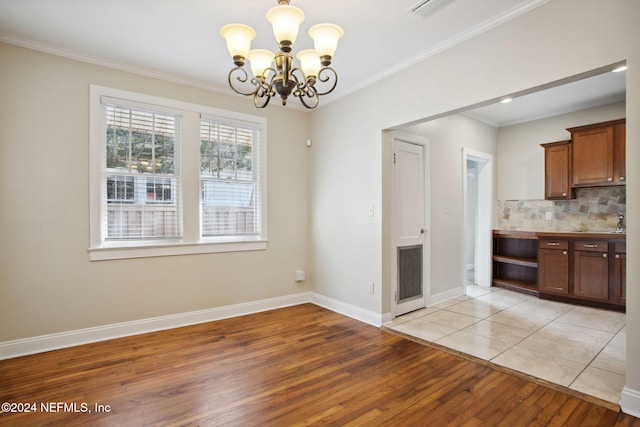 unfurnished dining area with a chandelier, light hardwood / wood-style floors, and ornamental molding