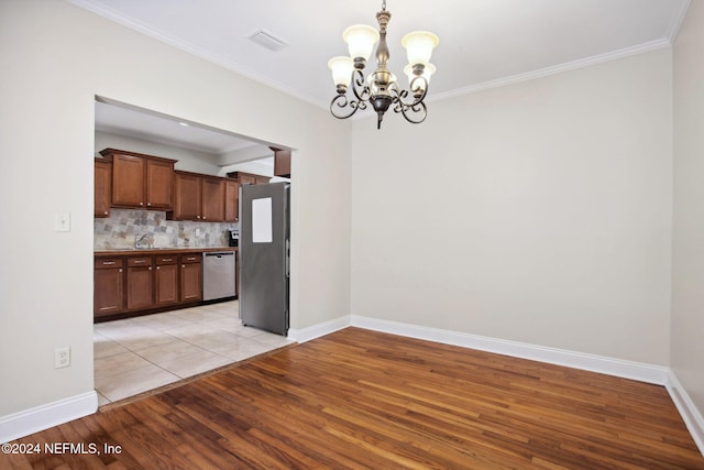 kitchen with backsplash, an inviting chandelier, crown molding, appliances with stainless steel finishes, and light hardwood / wood-style floors