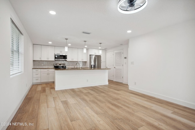 kitchen featuring stainless steel appliances, a kitchen island with sink, decorative light fixtures, light hardwood / wood-style floors, and white cabinetry