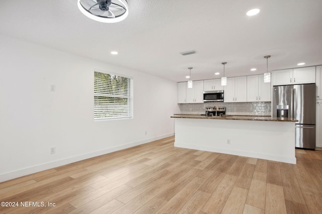 kitchen featuring stainless steel appliances, light hardwood / wood-style flooring, decorative light fixtures, a kitchen island with sink, and white cabinets