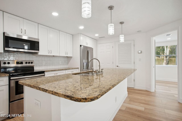 kitchen featuring sink, stainless steel appliances, white cabinetry, and an island with sink