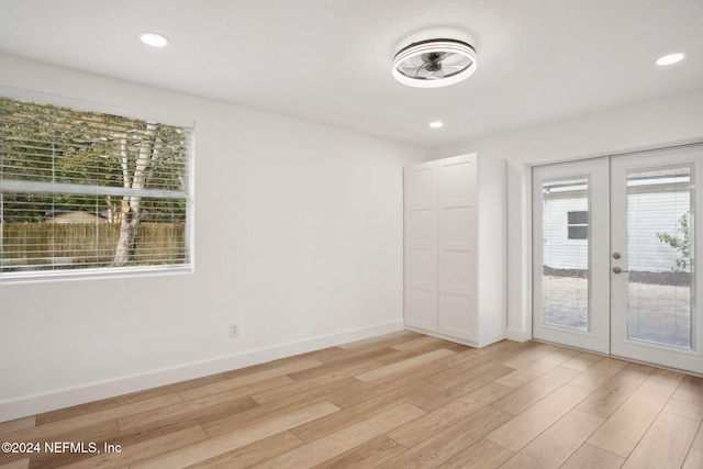 empty room featuring a wealth of natural light, french doors, and light wood-type flooring