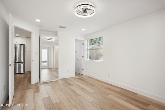 unfurnished bedroom featuring stainless steel fridge and light hardwood / wood-style flooring