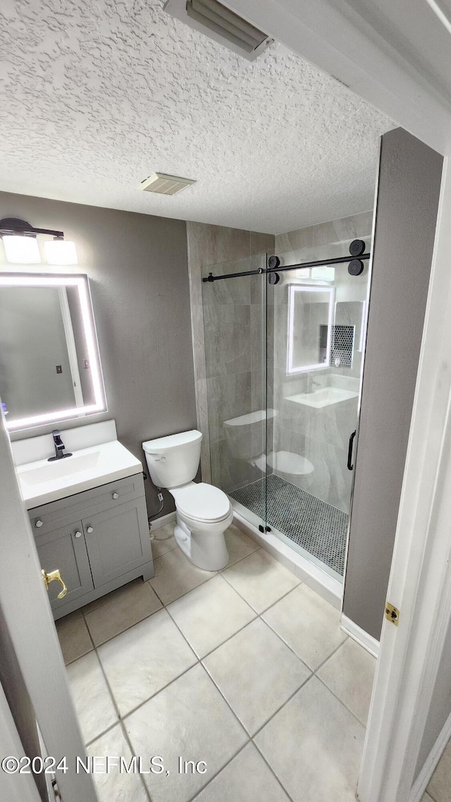 bathroom featuring tile patterned floors, an enclosed shower, vanity, a textured ceiling, and toilet