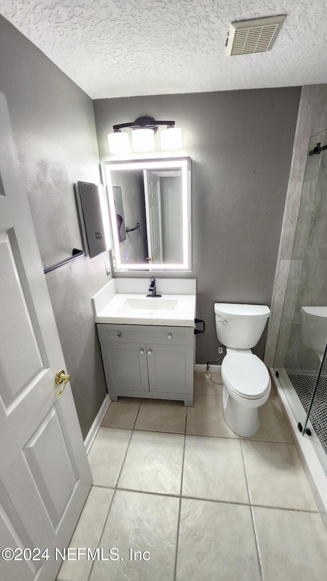 bathroom featuring toilet, a textured ceiling, and tile patterned floors