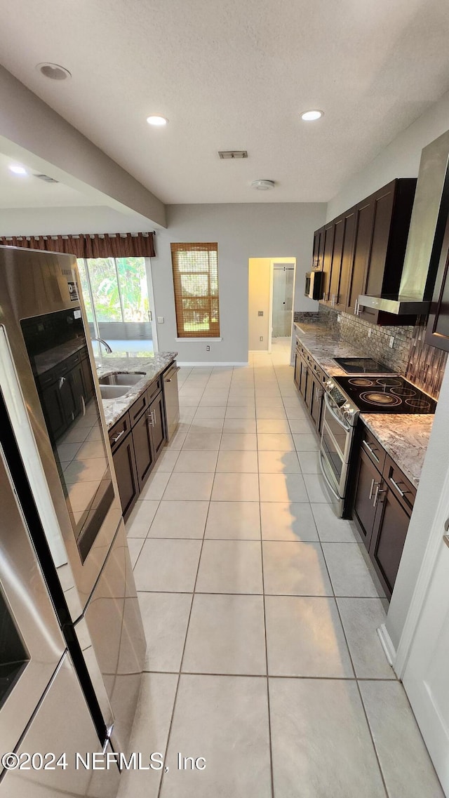 kitchen featuring light stone countertops, decorative backsplash, light tile patterned flooring, and sink