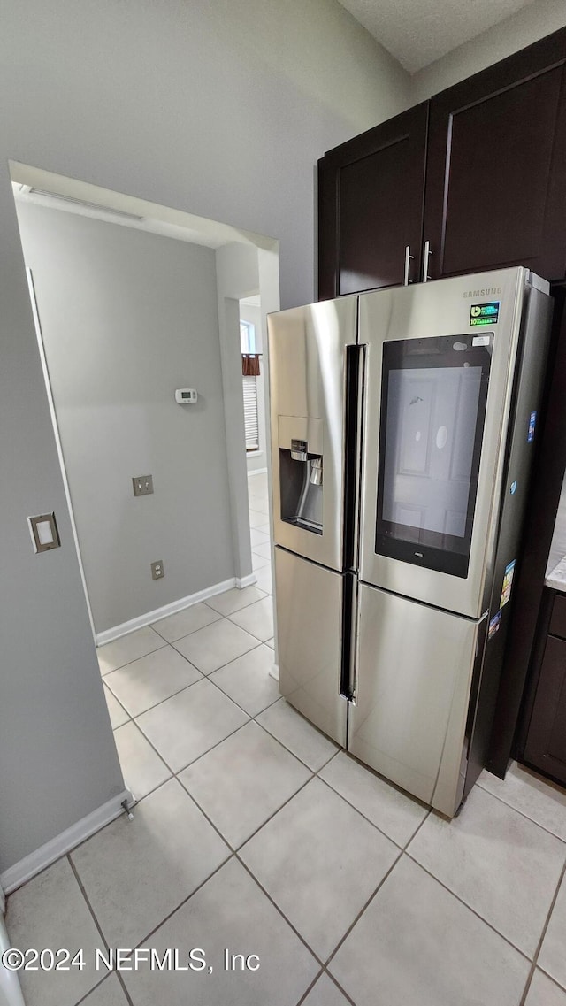 kitchen with dark brown cabinets, light tile patterned flooring, and stainless steel refrigerator with ice dispenser